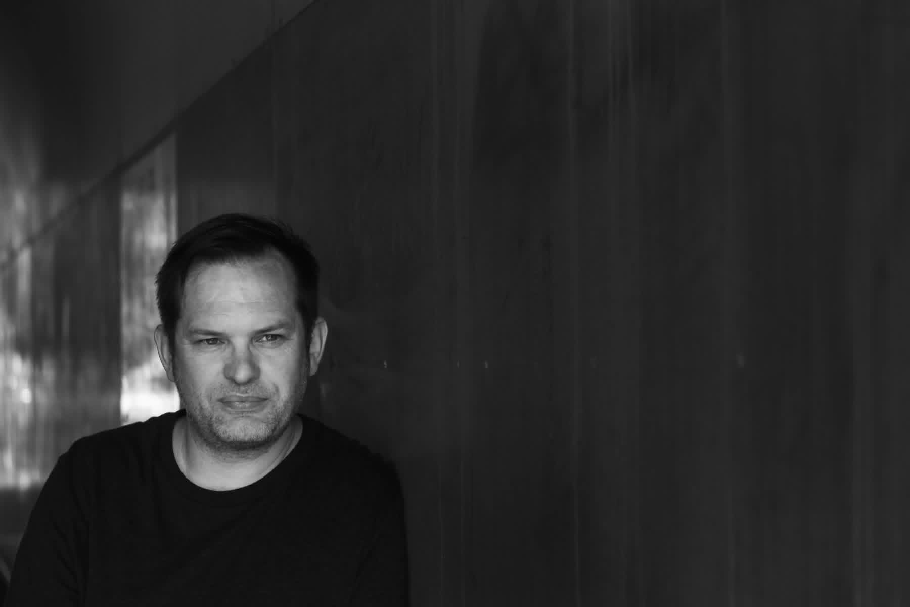 Black-and-white portrait of Phil Gwilliam in a shadowed passageway